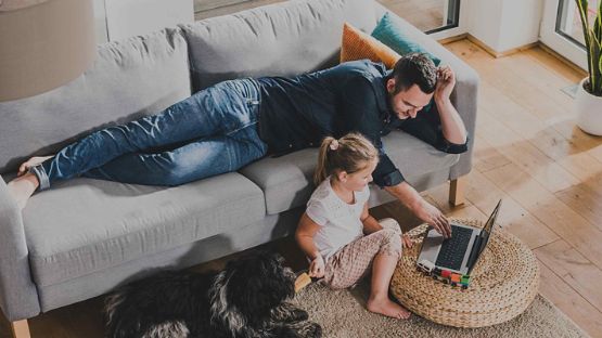 Père et sa fille utilisant un ordinateur portable dans le salon.