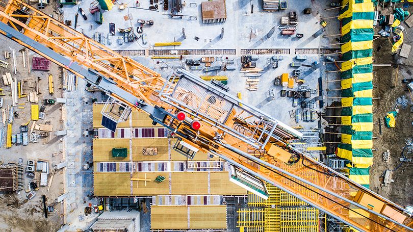 Birds eye view looking down on construction site with builders and crane.