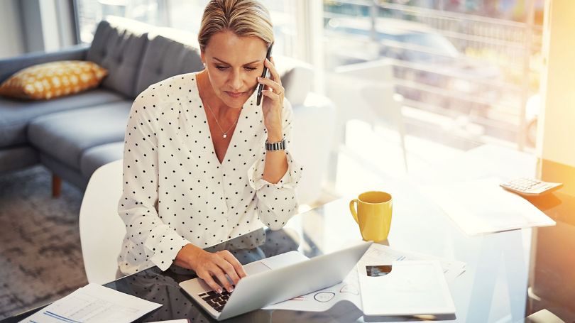Woman on phone call, looking at laptop