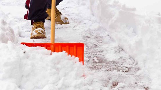 Une personne enlève la neige du trottoir à l’aide d’une pelle 