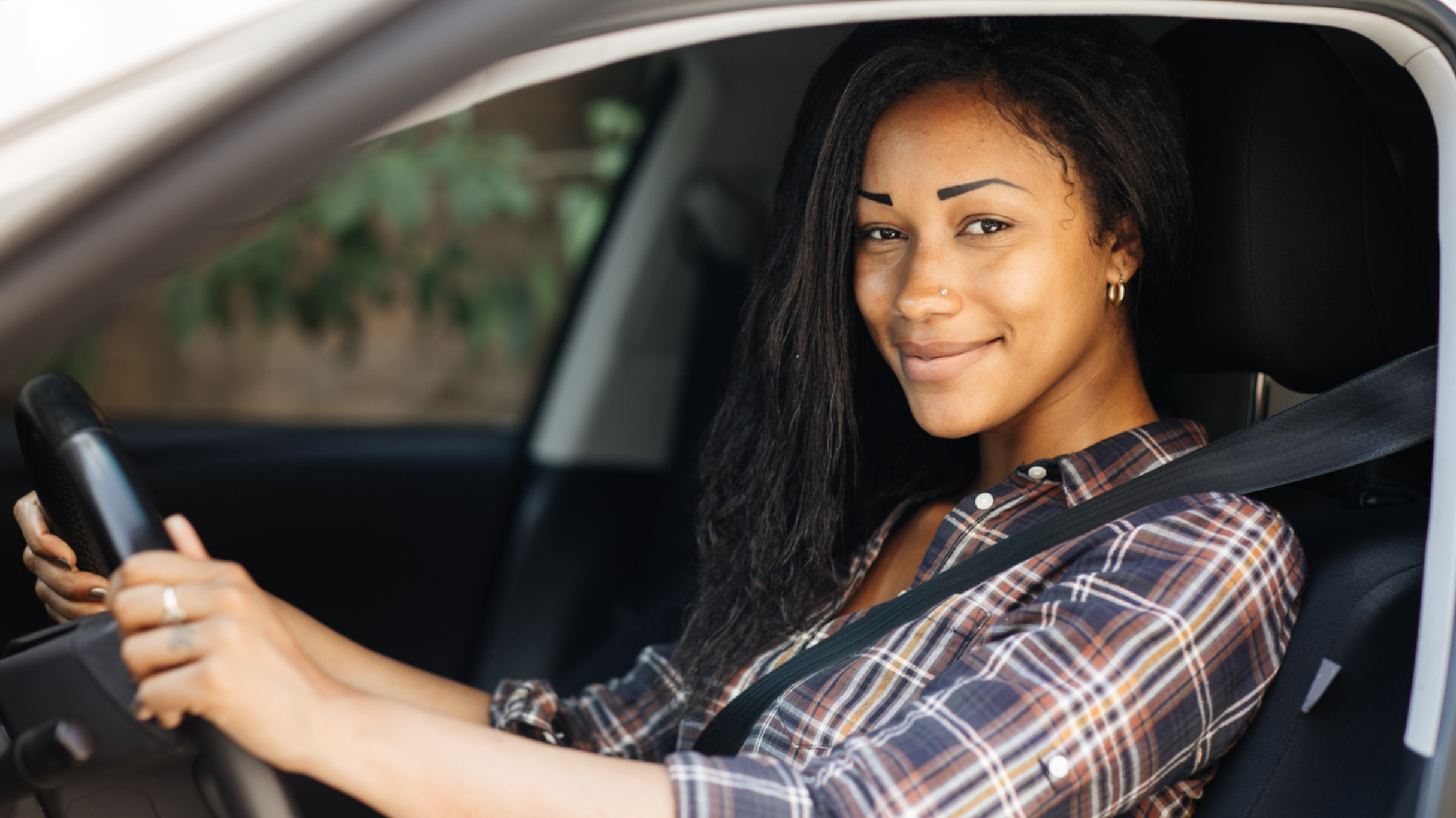 Woman smiling while sitting in the driver's seat of a car.