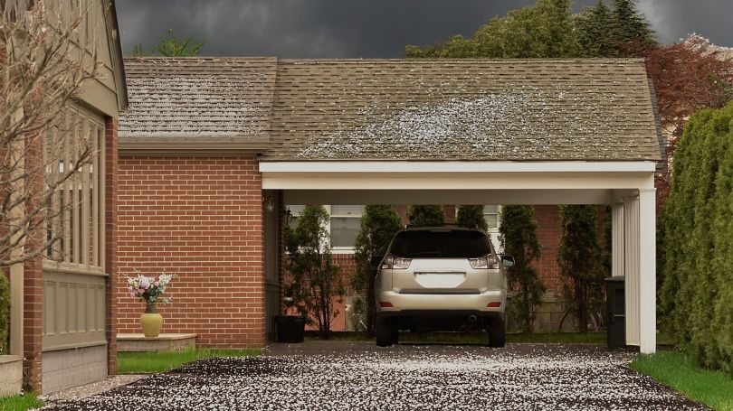 A car parks under a carport, protected from a hailstorm.