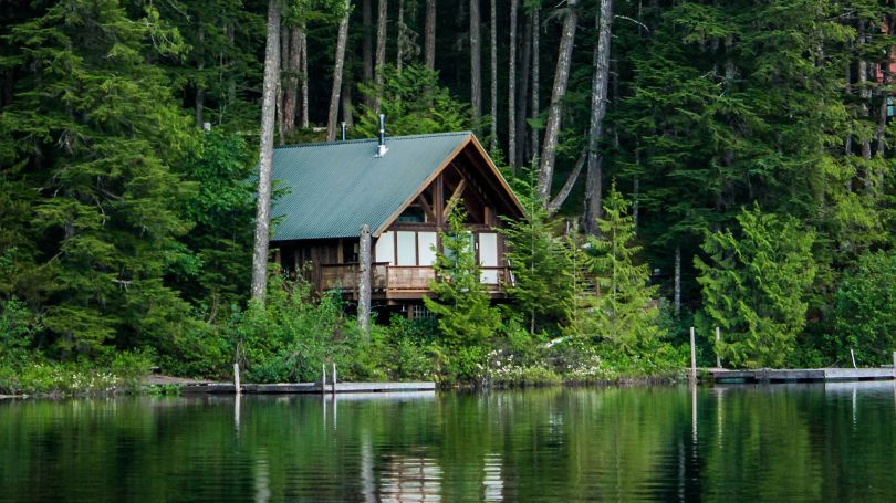 Un chalet entouré d'arbres au bord d'un lac