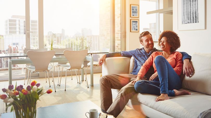 A happy couple enjoying a sunny afternoon on their living room couch in their condo