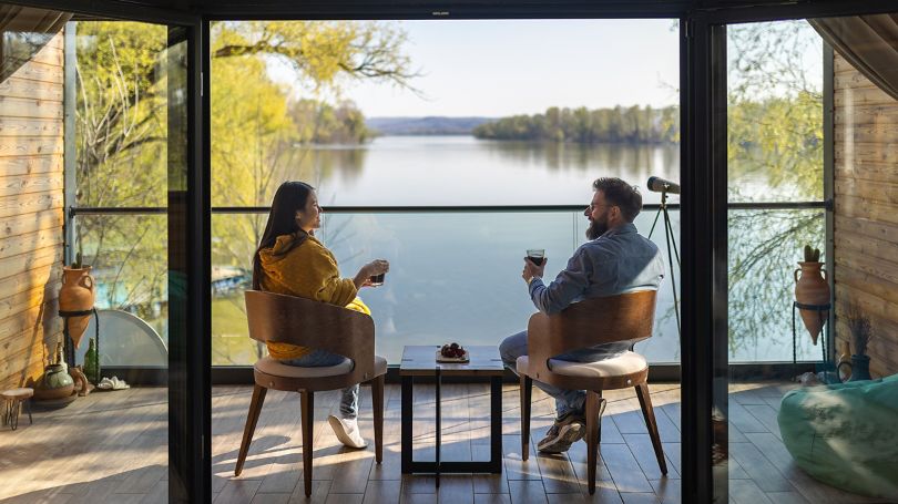 Un couple profitant d'une vue panoramique sur un lac paisible entouré d'arbres dans une cabane en bois confortable.