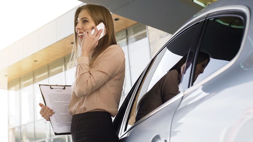 Driver taking business call beside parked car