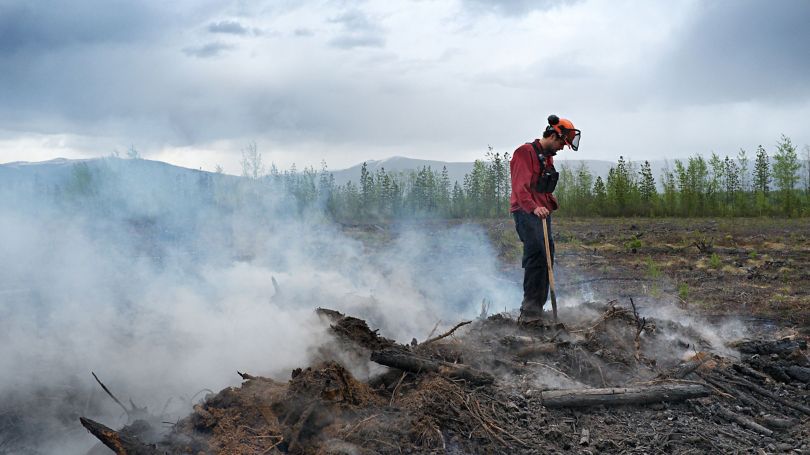 Firefighter standing on top of a smoldering pile