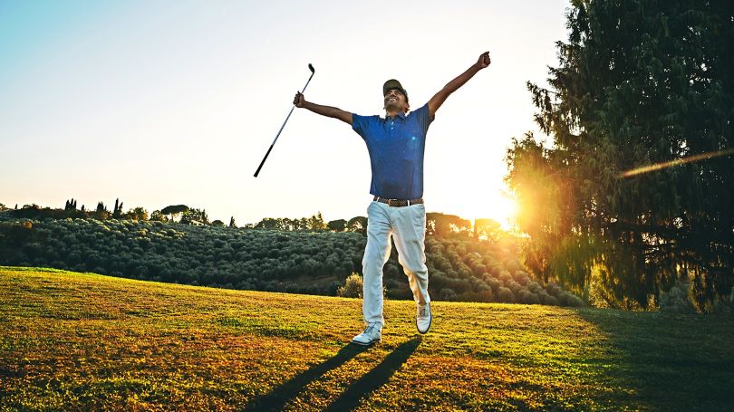Golfer appearing elated getting a hole-in-one on a beautiful day at the course.