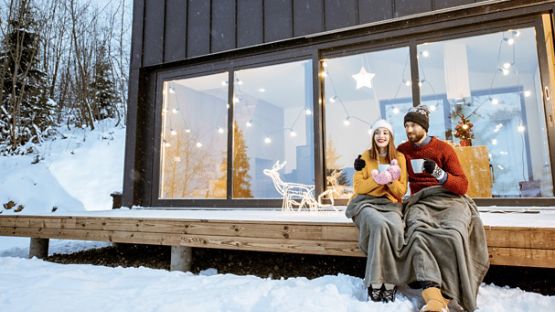 Happy couple sipping hot drinks on a cabin porch.