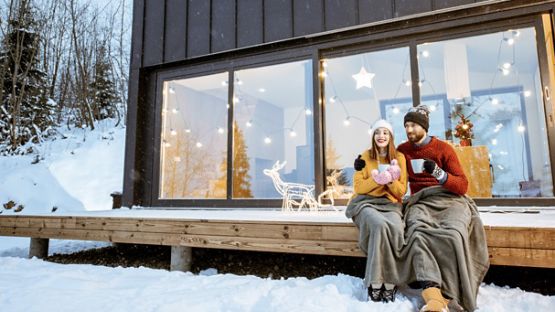 Couple ravi de savourer une boisson chaude sur le perron d’un chalet