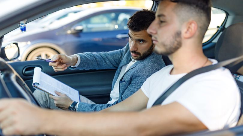 Driving instructor teaching new driver how to drive in a car