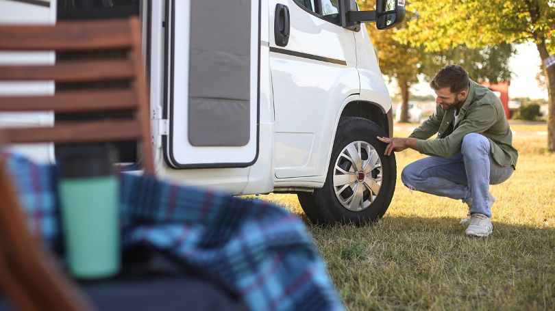 A man checking the tires on his recreational vehicle.