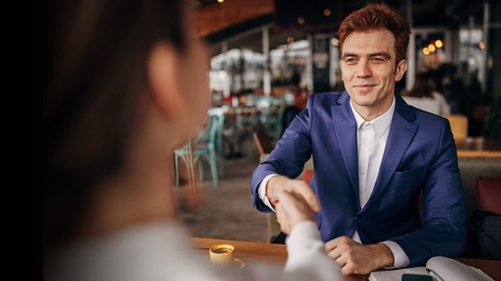 Man shaking someone’s hand across a desk.