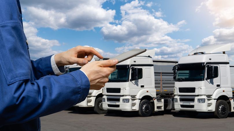 Manager with a digital tablet on the background of trucks
