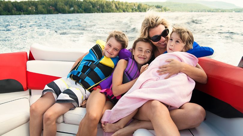 A mom with her three kids enjoying summer on a boat in the middle of the lake.