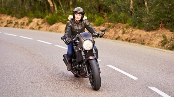 A rider on top of a futuristic looking motorcycle, enjoying a ride on an empty road.