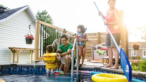 Parents surveillant les enfants dans la piscine, les enfants portant une veste de flottaison