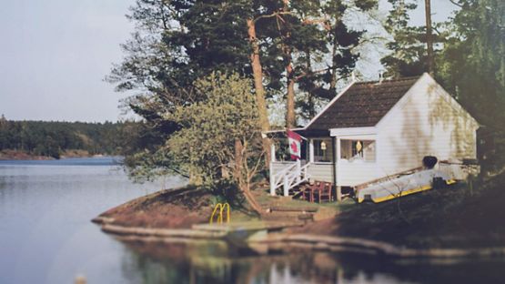 Rustic lakeside cabin flying a Canadian flag