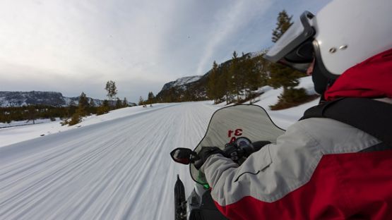 A shoulder view of a man enjoying a snowmobile ride.