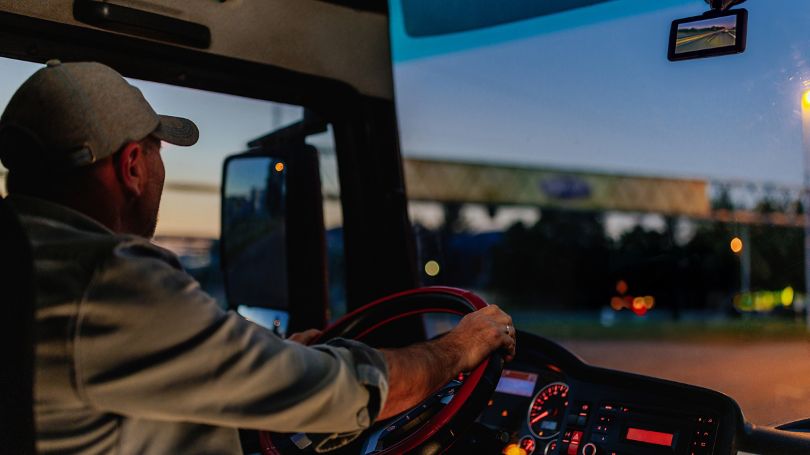 Intérieur d’un véhicule la nuit, montrant la caméra-témoin de circulation sur le tableau de bord et les phares des véhicules sur la route devant.