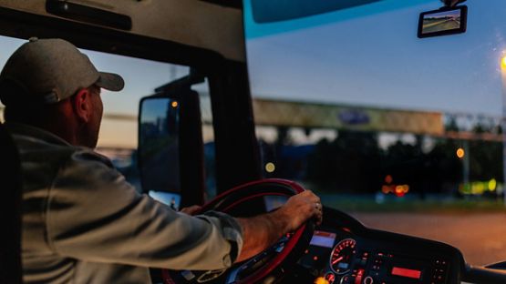 Intérieur d’un véhicule la nuit, montrant la caméra-témoin de circulation sur le tableau de bord et les phares des véhicules sur la route devant.