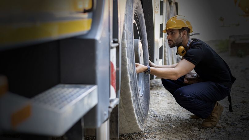 Trucker inspecting tire of a truck