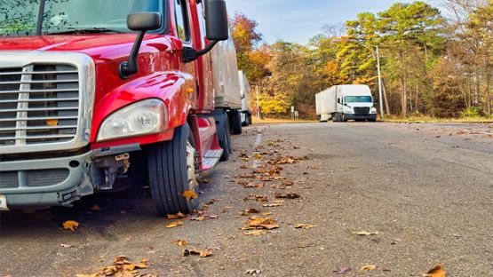 Transport trucks parked at a vehicle inspection station parking lot.