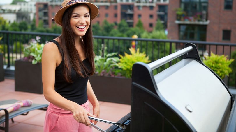 Young woman grilling food at barbecue outdoors