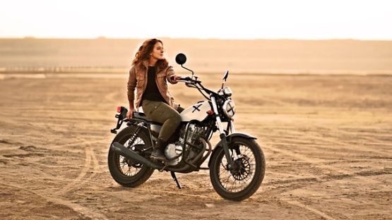 A rider sitting proudly on a vintage motorcycle.