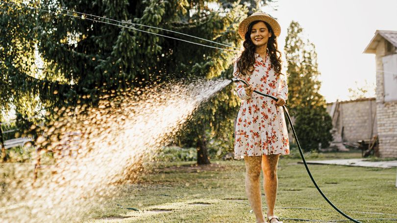 A woman waters her garden vegetation, which sits 20 feet from her home that features a fire-resistant, steel roof. 