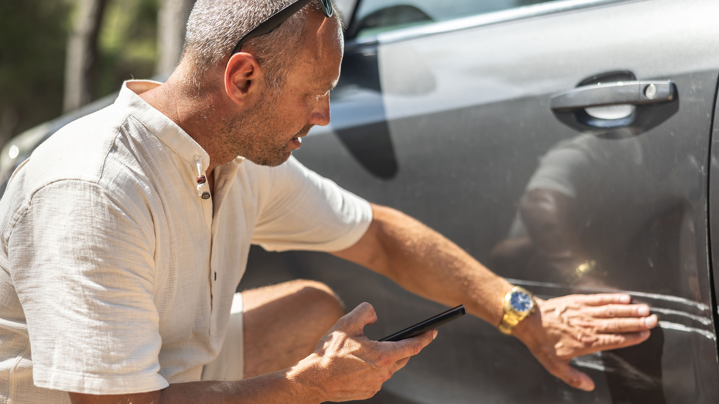 Person assessing damage to a parked vehicle.