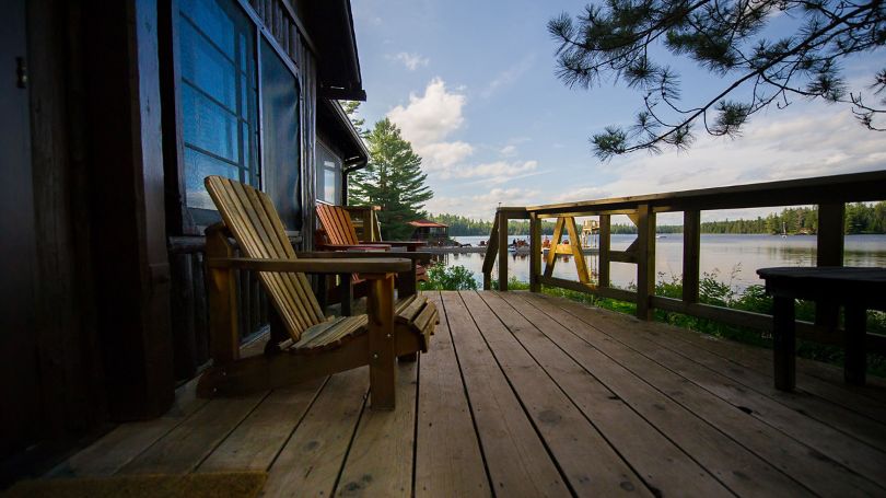 Muskoka chairs along a cottage front porch on a beautiful evening.