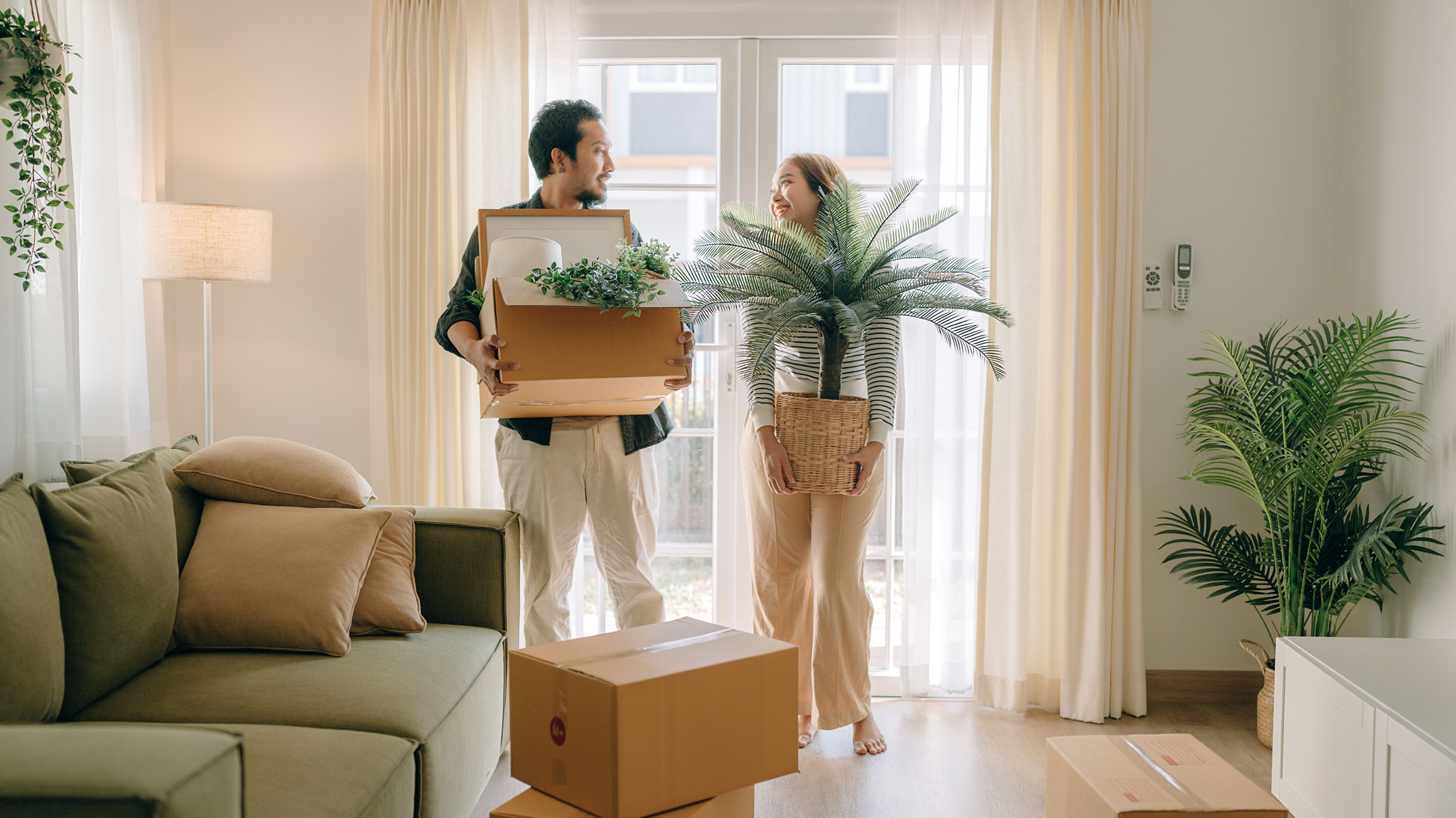 People moving boxes and belongings into a new home.
