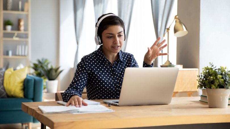 Woman working remotely interacting with coworkers.