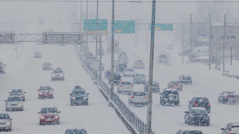 Multiple cars on a busy highway in the winter.