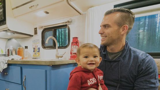 Smiling father and baby sitting inside RV.