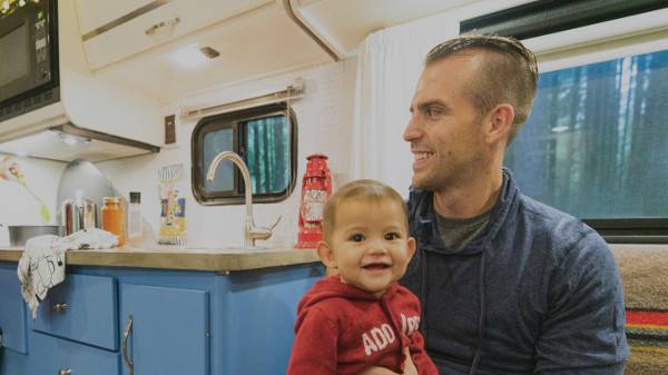 Smiling father and baby sitting inside RV.