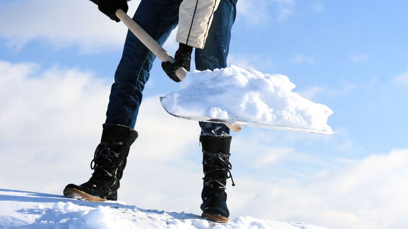 Man clearing snow off the roof of a house. 