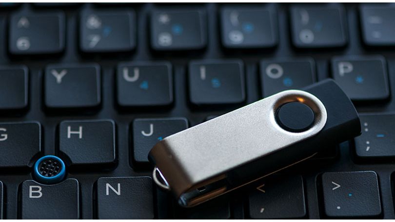 Close-up of a thumb drive sitting on top of a laptop keyboard.