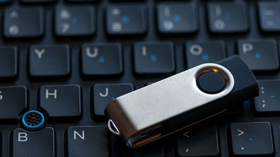 Close-up of a thumb drive sitting on top of a laptop keyboard.