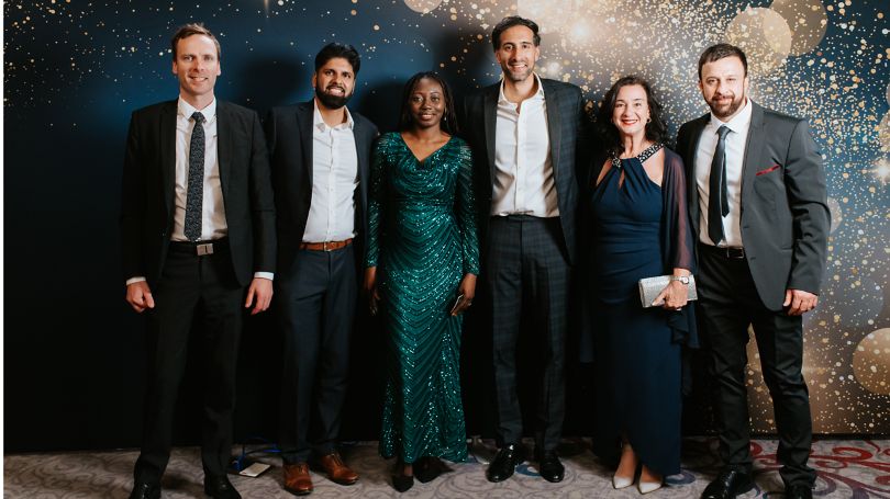 Six collègues posant devant un décor lors d'une cérémonie de remise de prix