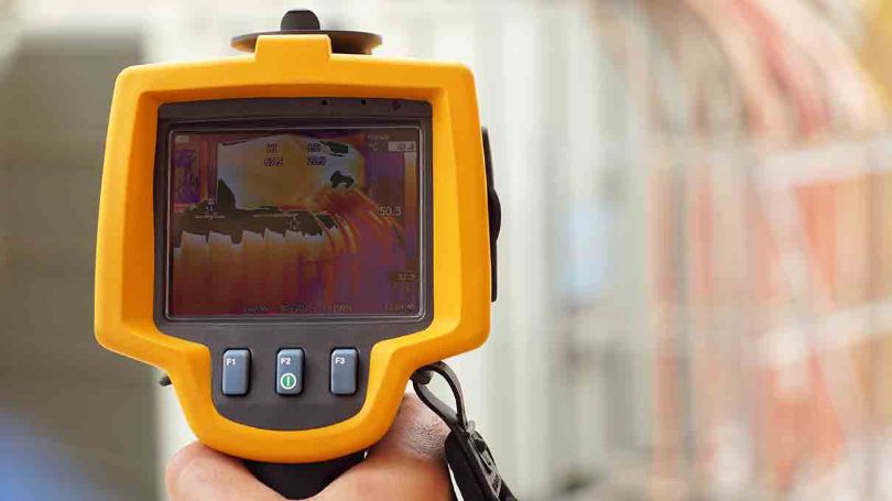 Technician using thermal imaging camera to check the temperature in a factory.
