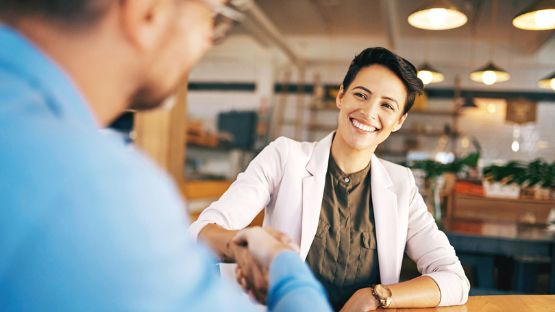 Woman shaking hands with a client in an office.