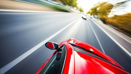 Red car speeding through the street.