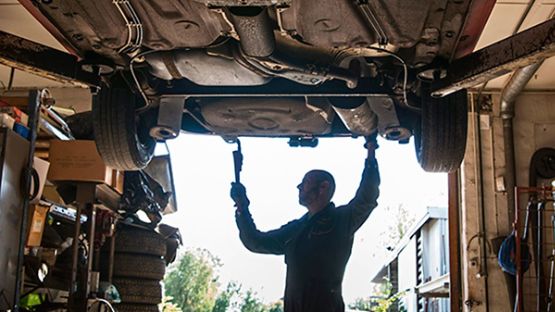 Mechanic working under a car in garage.