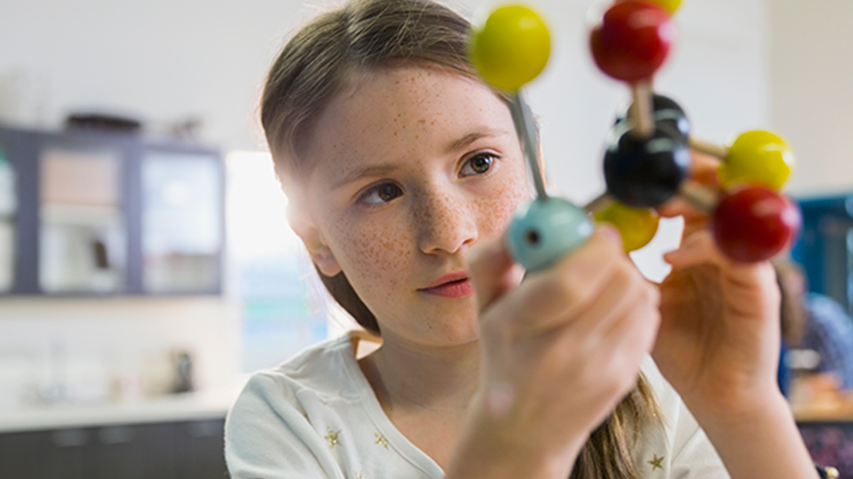 Student examining a molecular model during a science activity.