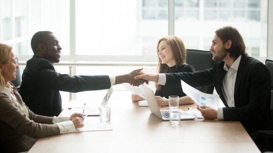 A claims service manager shaking hands with a corporate client.