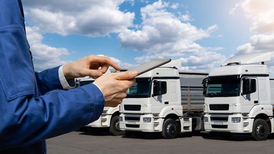 Gestionnaire avec une tablette numérique et une flotte de camions en arrière-plan