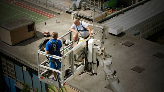 Three men inspecting the roof of a building