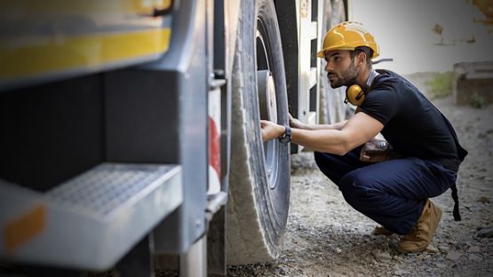 Trucker inspecting tire of a truck